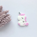 A collection of unicorn-shaped silicone teethers in various colors, including pink, blue, green, and purple, designed to be used by infants.