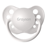 A white orthodontic pacifier with the name 'Grayson' engraved on the top.