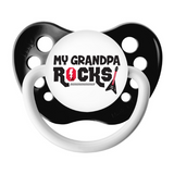 A black and white pacifier with the text 'MY GRANDPA ROCKS' engraved on it, designed for babies.