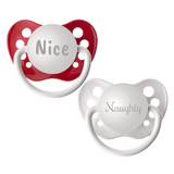 A set of two orthodontic pacifiers, one red with 'Nice' engraved on it and one white with 'Naughty' engraved, each with a protective cap attached.