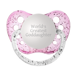A glitter pink pacifier with the inscription 'WORLD'S GREATEST GODDAUGHTER' engraved on the top, along with a clear silicone orthodontic nipple.