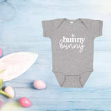 Gray bodysuit with 'Hunny Bunny' text on the front, displayed on a wooden surface with decorative elements around.